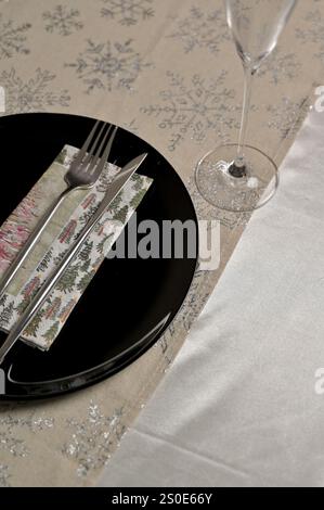 Christmas and New Year festive table setting for one person, black plate with fork and knife on snowflake pattern tablecloth Stock Photo