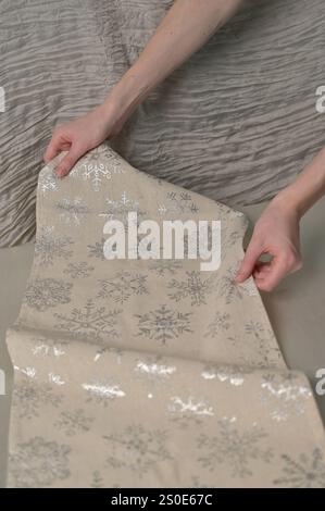 Christmas and New Year, woman hands cover the festive table with tablecloth snowflake pattern Stock Photo