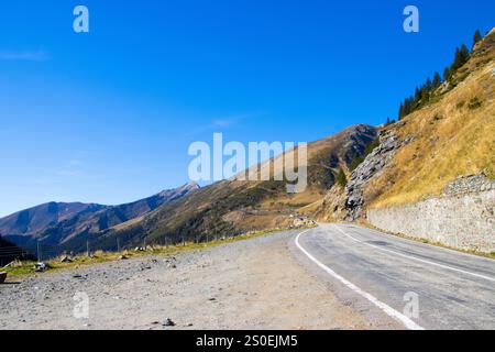 Road passing through Fagaras Mountains under a blue sky in Arges Coubty, Roman Stock Photo