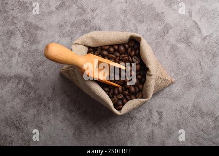 Sack and wooden scoop with roasted coffee beans isolated on dark cement background. Top view Stock Photo