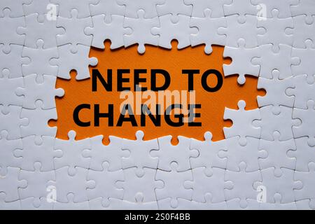 Need to change symbol. Concept words Need to change on white puzzle. Beautiful orange background. Business and Need to change concept. Copy space. Stock Photo