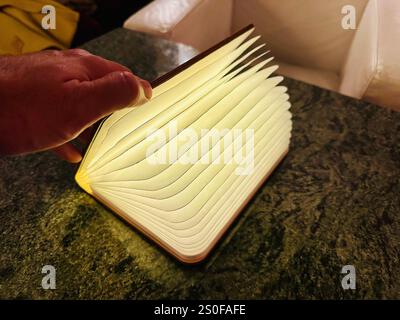 A book lamp on a table, pages are illuminated by an LED light within Stock Photo