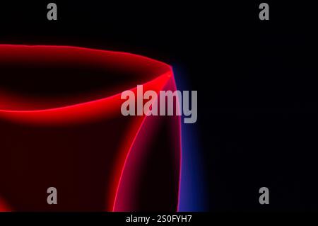Paper edges with neon reflections of colored light glowing on a black background for an abstract image with copy space Stock Photo
