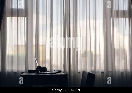 a notebook put on the wood table beside of the large window with curtain with nobody in the room of hotel or office in big city Stock Photo