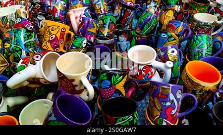 hand-painted ceramic coffee mugs and cups hand crafted by rural artisans from indian villages. The cups have vibrant colors and intricate patterns sho Stock Photo