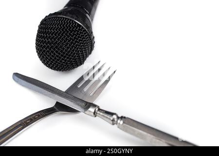 Black microphone next to fork and knife on a white plate, culinary blog concept Stock Photo