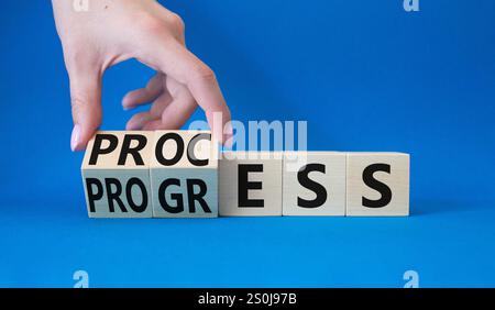 Process and Progress symbol. Hand turns wooden cubes and changes word Process to Progress. Beautiful blue background. Business and Process and Progres Stock Photo