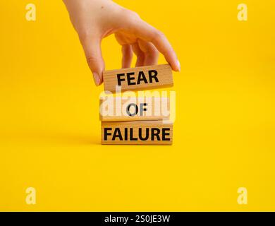 Fear of failure symbol. Concept words Fear of failure on wooden blocks. Beautiful yellow background. Businessman hand. Business and Fear of failure co Stock Photo