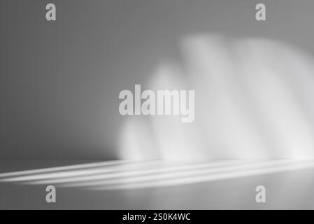 Soft abstract pattern of light and shadows on a smooth gray surface, creating a minimalist and atmospheric background. Stock Photo