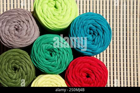 Colored skeins of thread for weaving macrame. Bright thread macro on a wooden background. Stock Photo