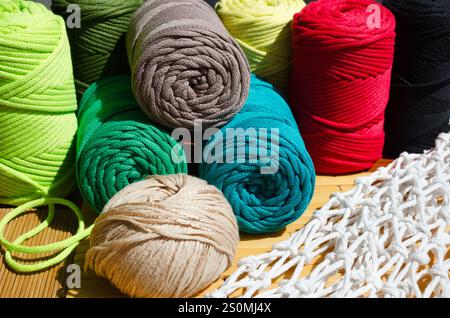 Colored skeins of thread for weaving macrame on a wooden surface. Stock Photo