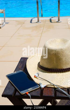 Accessories on the background of the blue pool. Hat, mobile phone and headphones. New Year holiday concept. Stock Photo