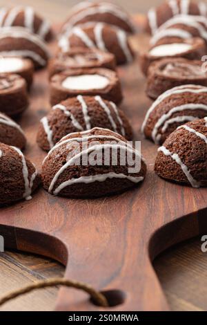 Baked goods: Round chocolate cookies with white glaze stripes. Ready to eat sweet treat. Stock Photo