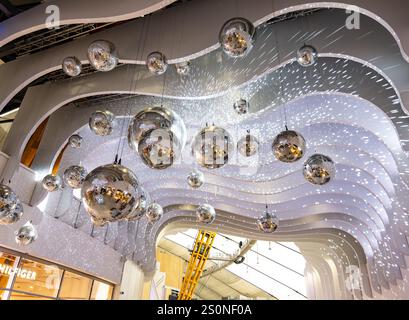 Futuristic interior design featuring reflective silver spheres and wave-like white ceilings with light effects in a modern building The O2 arena Stock Photo