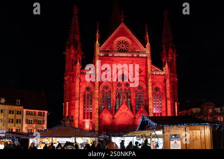 Mulhouse, France - December 6, 2024: Saint-Etienne Temple in Mulouse with lighting for the Christmas market, as crowds shop Stock Photo