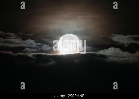 Bright full moon passing through late night clouds in Southern California. Stock Photo