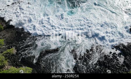 Where the deep blue ocean meets the rugged black rocks, creating nature's perfect contrast. Stock Photo
