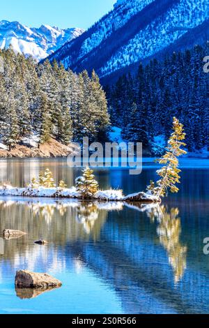 A snowy mountain range is reflected in the water of a lake. Concept of tranquility and serenity, as the peaceful scene of the snow-covered mountains a Stock Photo