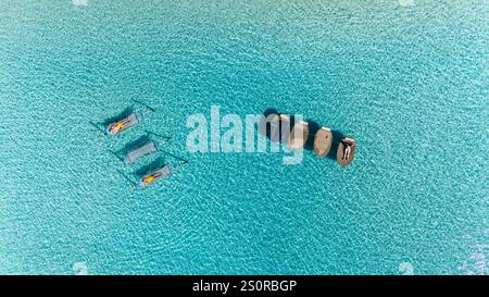 Sunbathers lounge on comfortable floats in the vibrant turquoise waters of Koh Kood, Thailand, enjoying a tranquil afternoon under the bright sun, a couple in hammock in the ocean Stock Photo