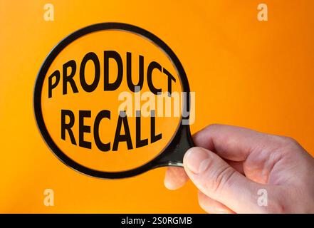 Product recall symbol. Concept words Product recall on magnifying glass. Beautiful orange background. Businessman hand. Business and Product recall co Stock Photo
