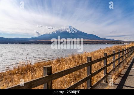 View of mount Fuji with background clouds and wooden fence at lake Kawaguchiko in foreground Stock Photo