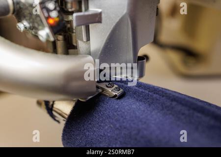 sewing machine overlock close-up in operation, outerwear production. Stock Photo