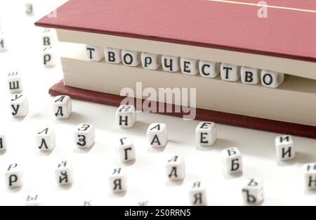 word creativity written win cyrillic letters between book sheets and cyrillic letters scatter on white background concept abstract Stock Photo