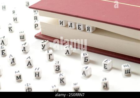 word idea written win cyrillic letters between book sheets and cyrillic letters scatter on white background concept abstract Stock Photo