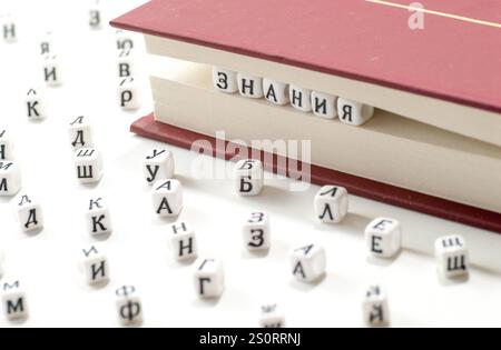 word knowledge written win cyrillic letters between book sheets and cyrillic letters scatter on white background concept abstract Stock Photo