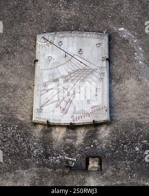 A sun dial mounted on a wall in Lourdes indicates the time using sunlight, reflecting historical craftsmanship and design. Stock Photo