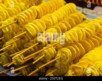 Spiral potatoes fried on a stick on a tray at a night market. Asian street food Thailand. Stock Photo