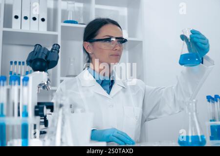 A skilled female scientist is analyzing chemical solutions in a modern lab, demonstrating her professionalism and innovative research, contributing Stock Photo