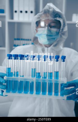 A Laboratory Technician skillfully analyzing a variety of test tubes filled with vibrant blue solutions, contributing to critical research in the Stock Photo