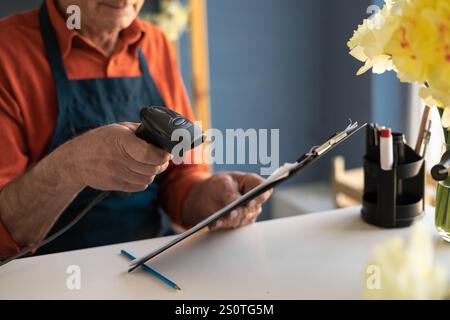 elderly male florist reads barcode to arrange delivery . He does this using scanner. Copy space Stock Photo