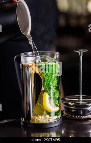 vitamin tonic tea with lemon, ginger and mint, on a dark background in a transparent teapot, Stock Photo