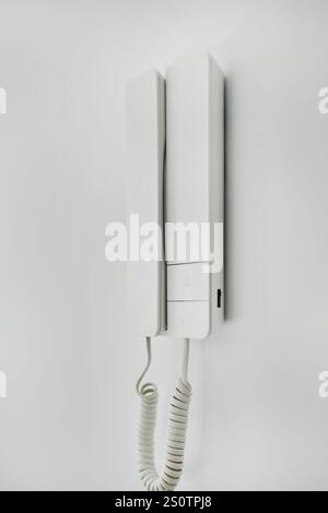 Close up simple, modern home intercom system with buttons or controls for communication and potentially for unlocking door, mounted on white wall Stock Photo