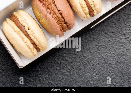 Macaroons in a black cardboard box on a dark background. Stock Photo