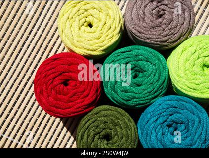Colored skeins of thread for weaving macrame. Bright thread macro on a wooden background. Stock Photo