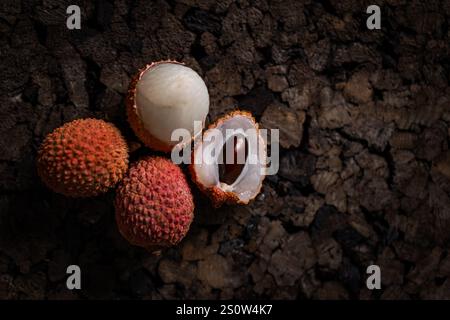 Close up of three lychees on a textured dark surface, creating a contrast of colors and textures Stock Photo