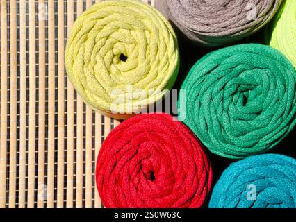 Colored skeins of thread for weaving macrame on a wooden surface. Cotton threads for knitting. Stock Photo