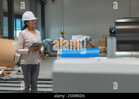 Young Indian woman, a successful production manager using a tablet during factory inspection. Manufacturing and business concepts. Stock Photo
