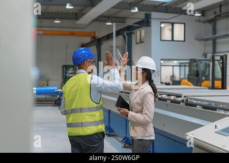 Female manager engineer giving high five to industry worker in manufacture factory. Stock Photo