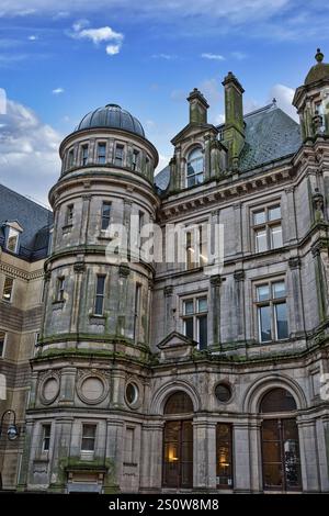 A grey stone building with a dome, multiple windows, and arched entrances. The building shows signs of age and weathering, with visible moss or lichen Stock Photo