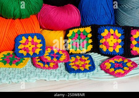 Knitted zigzag handmade ornaments and skeins of multi-colored threads. Colorful cotton granny square. Crochet texture close up photo. Stock Photo