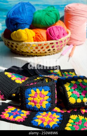 Knitted zigzag handmade ornaments and skeins of multi-colored threads. Colorful cotton granny square. Crochet texture close up photo. Stock Photo