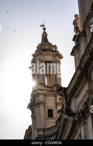 Baroque architecture with a tower and sunlight streaming through the structures, Rome Stock Photo