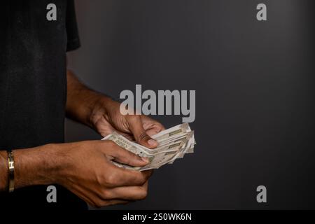 Hands counting Indian Rupees against a dark background.  Concepts of finance, budgeting, and personal wealth. Stock Photo