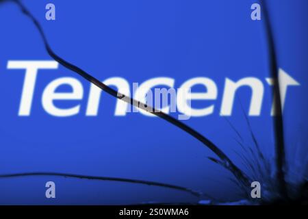 Tencent logo is visible on the broken glass. Tencent Holdings Ltd is a Chinese multinational technology conglomerate and holding company. Stock Photo