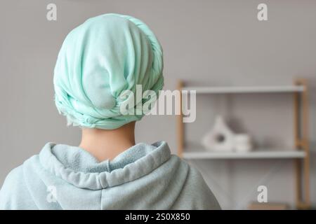 Young woman in headscarf after chemotherapy at home, back view. Cervical Health Awareness Month Stock Photo
