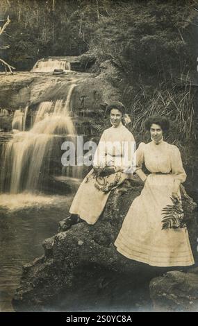 Two young women in long white dresses, aged 17 and 20 at a waterfall near Leura in the Blue Mountains, New South Wales, Australia in 1910 Stock Photo